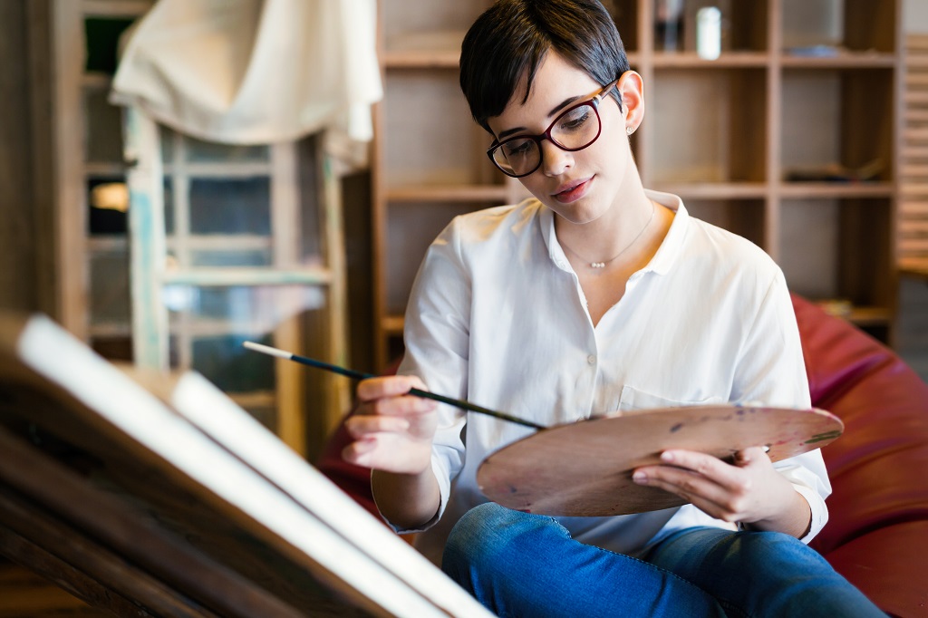 Female artist painting with palette and paintbrush
