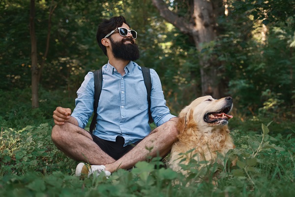 Man resting on the grass sitting crossed legs with his dog