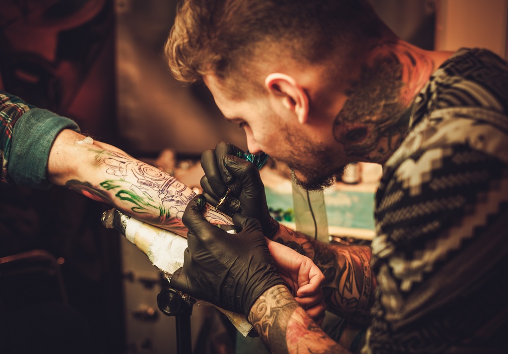 Tattoo artist makes a tattoo on a man’s hand.