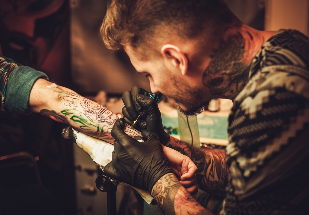 Tattoo artist makes a tattoo on a man’s hand.